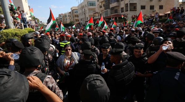 epa10925636 Members of the security forces stand guard in front of protesters holding Palestinian flags during a pro-Palestinian rally near the Israeli embassy following a strike on a hospital in the Gaza Strip, in Amman, Jordan, 18 October 2023. According to Palestinian authorities in Gaza hundreds of people have been killed in the explosion at a hospital in Gaza on 17 October. Israel has denied responsibility and said a Palestinian Islamic Jihad (PIJ) rocket misfire caused the blast.  EPA/MOHAMMAD ALI