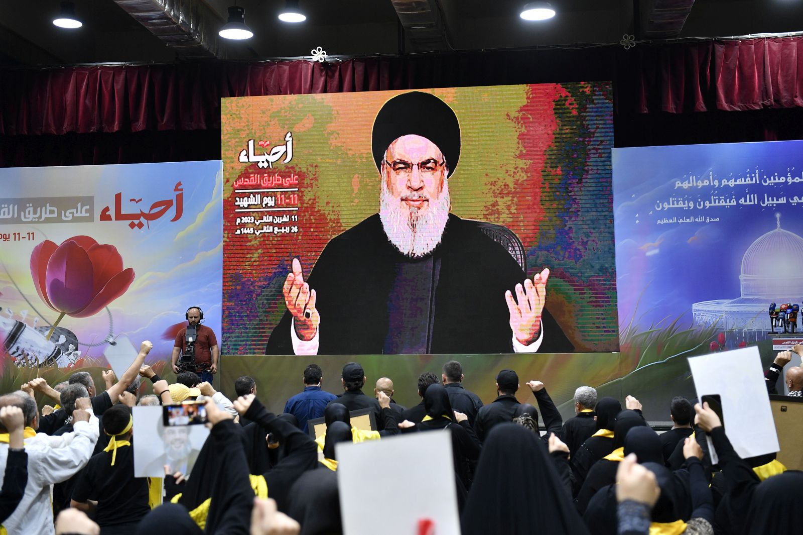 epa10970227 Hezbollah supporters raise their hands as they listen to a speech by Hezbollah leader Hassan Nasrallah, shown on a large screen, on the occasion of Hezbollah's annual 'Martyrs' Day', in the southern suburb of Beirut, Lebanon, 11 November 2023. In his speech, Hezbollah leader Hassan Nasrallah commented on the ongoing conflict between Israel and Hamas.  EPA/WAEL HAMZEH