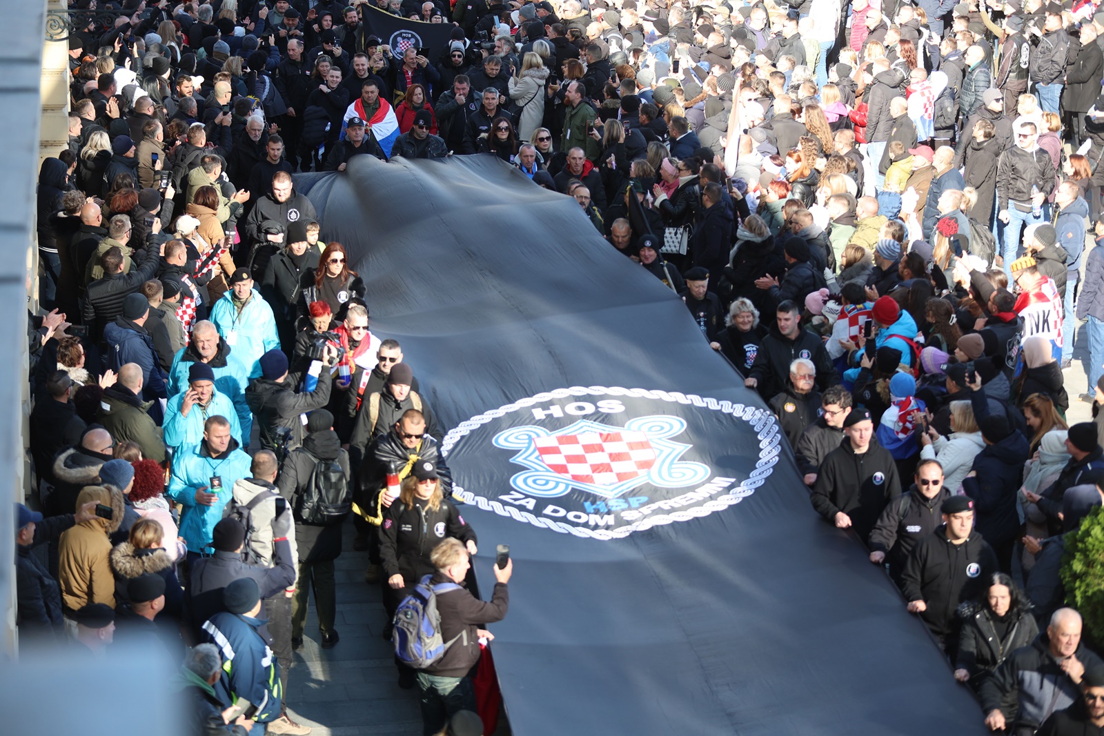 Vukovar, 18.11.2023 - Pod geslom "Vukovar - moj izbor i u dobru i u zlu" u Vukovaru se obiljeava 32. godinjica vukovarske tragedije i stradanja u Domovinskom ratu. Kolona sjeæanja koju predvode hrvatski branitelji Vukovara zajedno s èlanovima obitelji poginulih, nestalih, ubijenih, nasilno odvedenih i umrlih hrvatskih branitelja Vukovara na èelu s pripadnicima Hrvatskih obrambenih snaga koji su branili Vukovar. Na slici velika zastava HOS-a. foto HINA/ Damir SENÈAR/ ds