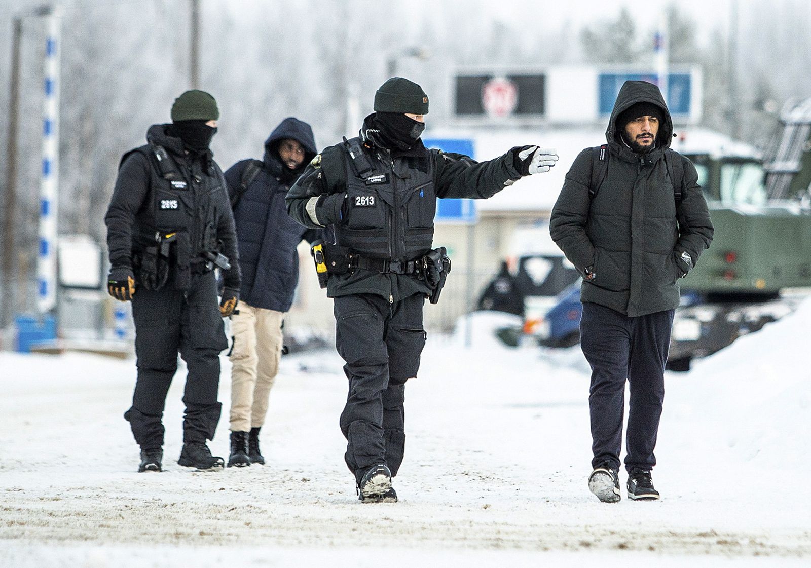 epa10987851 Asylum seekers are accompanied by Finnish border police personnel as they arrive at the border station Vartius in northern Finland near Kuhmo, Finland, 21 November 2023. Finland has closed crossing points on its border to Russia as more asylum seekers try to get to Finland through the border stations in Northern Finland.  EPA/JANNE KURONEN