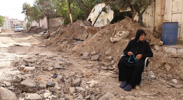 epa10996009 People woman sits amidst the rubble in a street after an Israeli raid on the Jenin refugee camp in the West Bank city of Jenin, 26 November 2023. According to the Palestinian Health Ministry, five Palestinians were killed and 15 others injured in the overnight Israeli raid on the Jenin camp and ensuing clashes.  EPA/ALAA BADARNEH