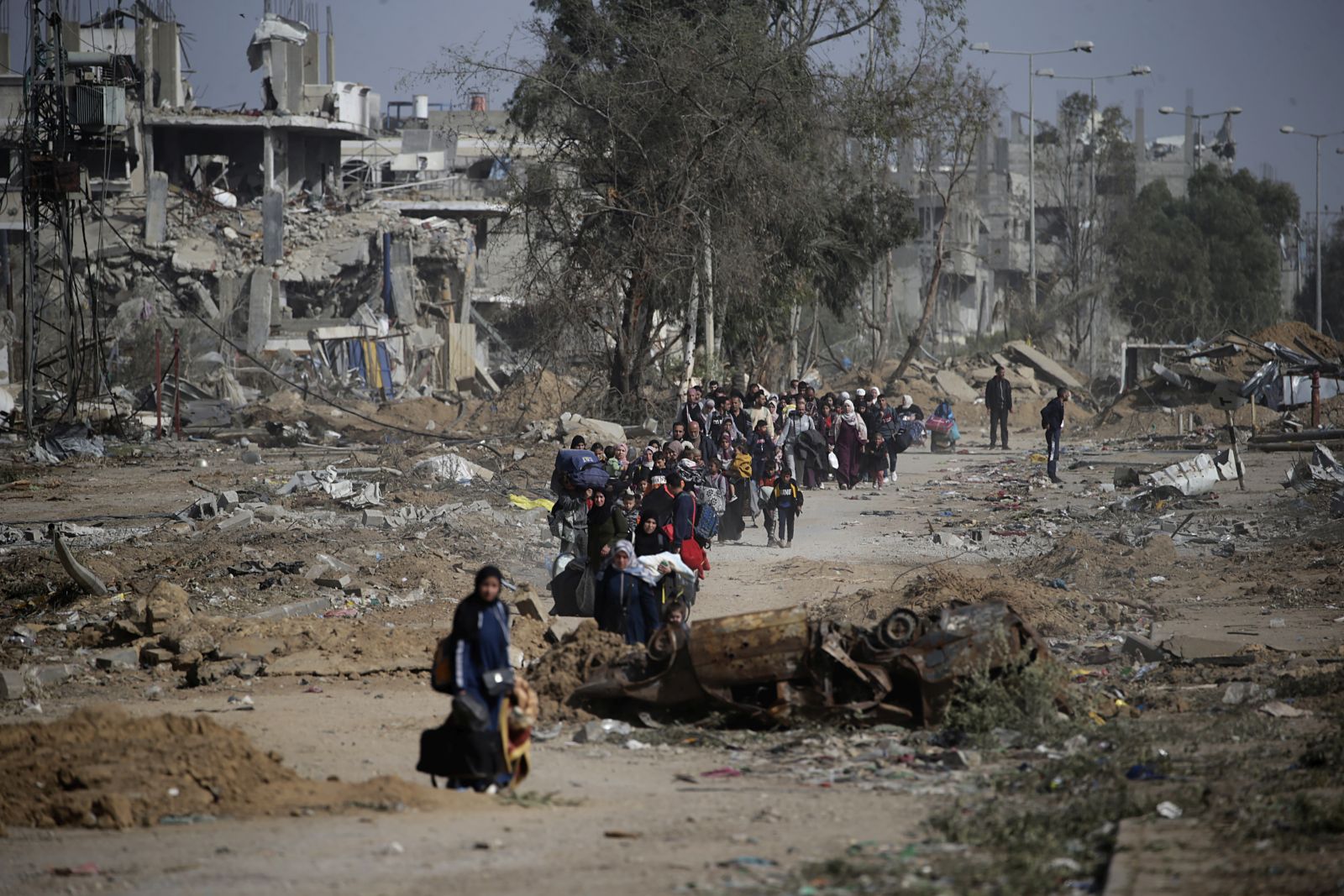 epa10996187 Palestinians walk after crossing from the northern Gaza Strip to the southern Gaza Strip as Israeli tanks (not pictured) move along Salah Al Din road, in the central Gaza Strip, 26 November 2023. After Israel and Hamas agreed to a four-day ceasefire, mediated by Qatar, the US, and Egypt, that came into effect at 05:00 AM GMT on 24 November, some Palestinians who were still in central Gaza moved towards the south while others already displaced in the south went back to the northern part to check on relatives they had left behind and on their homes to collect salvageable belongings. As part of the ceasefire, the agreement included that 50 Israeli hostages, women and children, are to be released by Hamas. 150 Palestinian women and children that were detained in Israeli prisons are to be released in exchange.  EPA/MOHAMMED SABER
