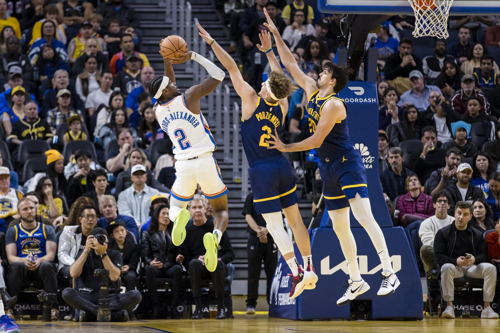 Nov 18, 2023; San Francisco, California, USA; Golden State Warriors guard Brandin Podziemski (2) and center Dario Saric (20) defend Oklahoma City Thunder guard Shai Gilgeous-Alexander (2) during the second half at Chase Center. Mandatory Credit: John Hefti-USA TODAY Sports Photo: John Hefti/REUTERS