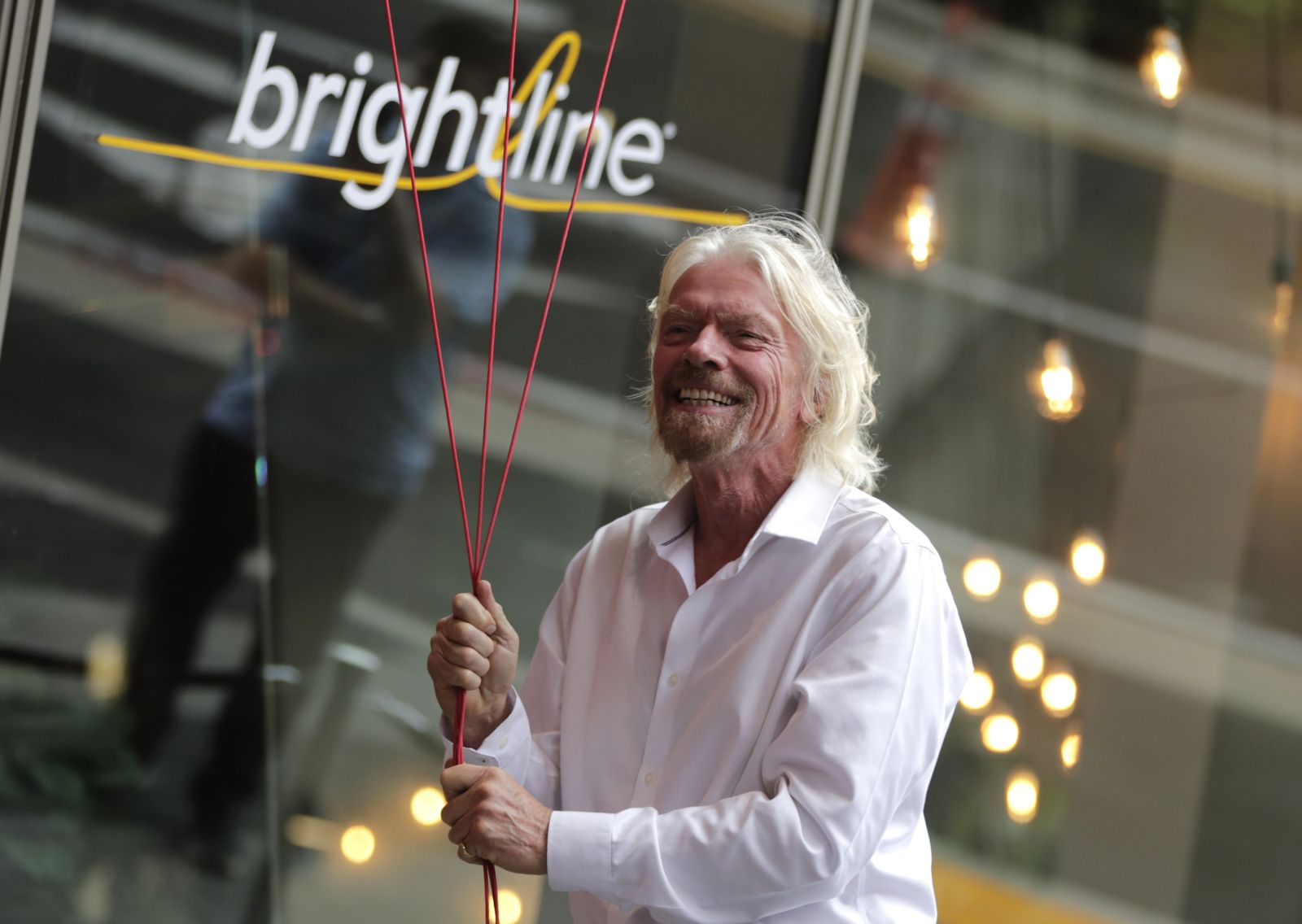 FILE - Richard Branson, of Virgin Group, prepares to unfurl a banner during a naming ceremony for the Brightline train station, to be renamed as Virgin MiamiCentral in Miami on April 4, 2019. A British judge ruled in favor of Richard Branson's Virgin group on Thursday Oct. 12, 2023 in its lawsuit against a U.S. train company that terminated a licensing agreement and claimed the Virgin brand was no longer one of “high repute.” (AP Photo/Lynne Sladky, File)