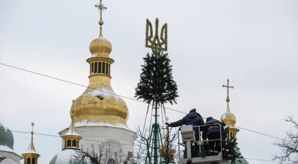 epa11010824 Workers place the State emblem on top of a Christmas tree in front of Saint Sophia's Cathedral in Kyiv, Ukraine, 04 December 2023 This year Ukraine will mark Christmas on the 25 December together with Europe, unlike in previous years when Ukraine marked Christmas on 07 January with other post-Soviet countries. Russian troops entered Ukraine on 24 February 2022 starting a conflict that has provoked destruction and a humanitarian crisis.  EPA/SERGEY DOLZHENKO