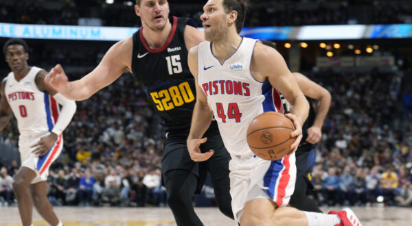 Detroit Pistons forward Bojan Bogdanovic (44) drives past Denver Nuggets center Nikola Jokic (15) in the second half of an NBA basketball game Sunday, Jan. 7, 2024, in Denver. (AP Photo/David Zalubowski)