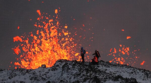 epa11037614 A team of scientists works on the ridge of a volcanic fissure as lava spews during a volcanic eruption, near the town of Grindavik, in the Reykjanes peninsula, southwestern Iceland, 19 December 2023. The Icelandic Meteorological Office (IMO) announced the start of a volcanic fissure eruption near the Sundhnuka crater, north-east of Grindavik, on the night of 18 December, following weeks of intense earthquake activity in the area. The power and seismic activity of the eruption have decreased over time, IMO reported on 19 December, adding that since the eruption began, about 320 earthquakes have been recorded.  EPA/ANTON BRINK