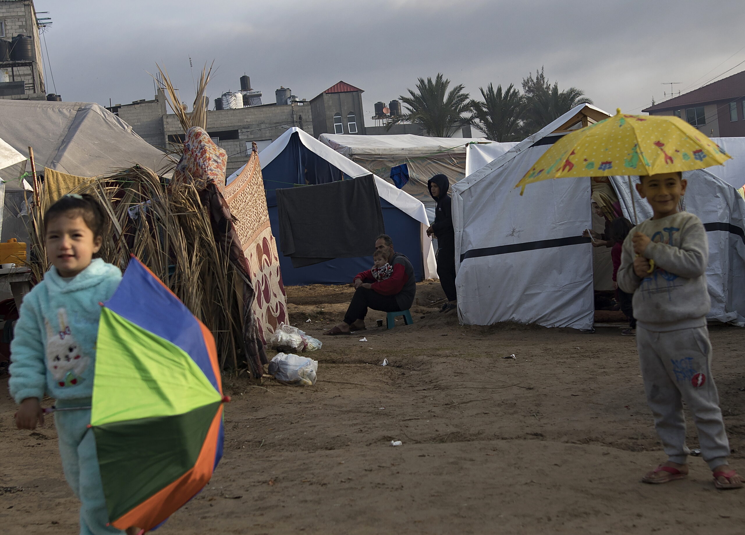 epa11053202 Displaced children hold umbrellas after a rainy night at a camp near Nasser Hospital in Khan Yunis, southern Gaza Strip, 02 January 2024. More than 21,800 Palestinians and at least 1,300 Israelis have been killed, according to the Palestinian Health Ministry and the Israel Defense Forces (IDF), since Hamas militants launched an attack against Israel from the Gaza Strip on 07 October 2023, and the Israeli operations in Gaza and the West Bank which followed it. Since 07 October, up to 1.9 million people, or more than 85 percent of the population, have been displaced throughout the Gaza Strip, some more than once, according to the United Nations Relief and Works Agency for Palestine Refugees in the Near East (UNRWA), which added that most civilians in Gaza are in 'desperate need of humanitarian assistance and protection'.  EPA/HAITHAM IMAD