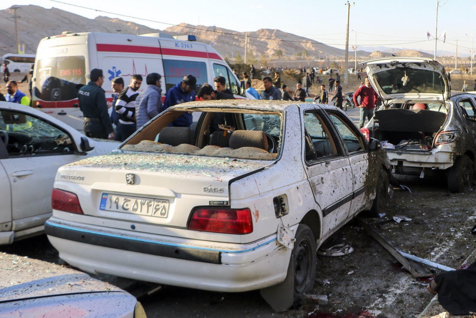 epa11055381 Damaged cars are seen as people try to help victims after an explosion next to the tomb of Iran's Revolutionary Guards chief of foreign operations in the Saheb al-Zaman mosque in the southern city of Kerman, Iran 03 January 2024. On the fourth anniversary of the US-initiated assassination of Iranian General Qasem Soleimani, two bomb explosions have killed at least 103 people and another 171 people were wounded close to his mausoleum, according to Iranian official television. As part of a ceremony to honor General Soleimani, who was killed in a US drone strike in neighboring Iraq in 2020, hundreds of people were on their way towards the grave on 03 January.  EPA/TASNIM NEWS AGENCY