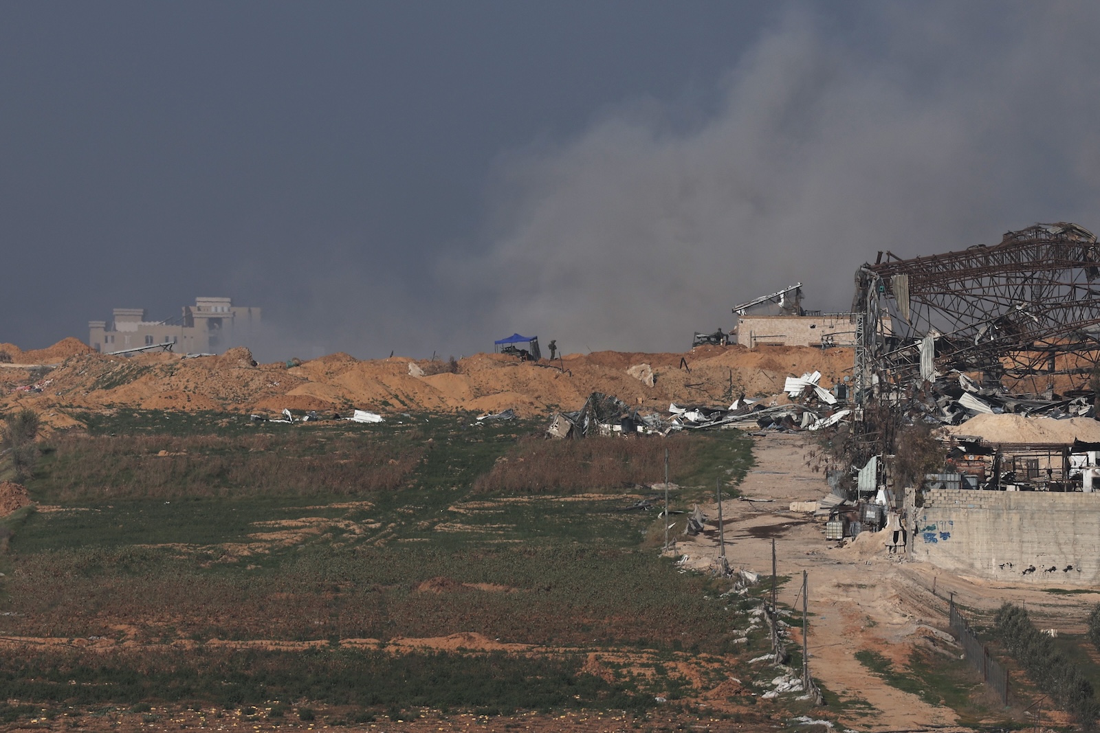epa11067078 Israeli troops in position as smoke rises over Buraij refugee camp in the central Gaza Strip, as seen from an undisclosed location in Israel 10 January 2024. More than 22,800 Palestinians and at least 1,300 Israelis have been killed, according to the Palestinian Health Ministry and the Israel Defense Forces (IDF), since Hamas militants launched an attack against Israel from the Gaza Strip on 07 October, and the Israeli operations in Gaza and the West Bank which followed it.  EPA/ATEF SAFADI