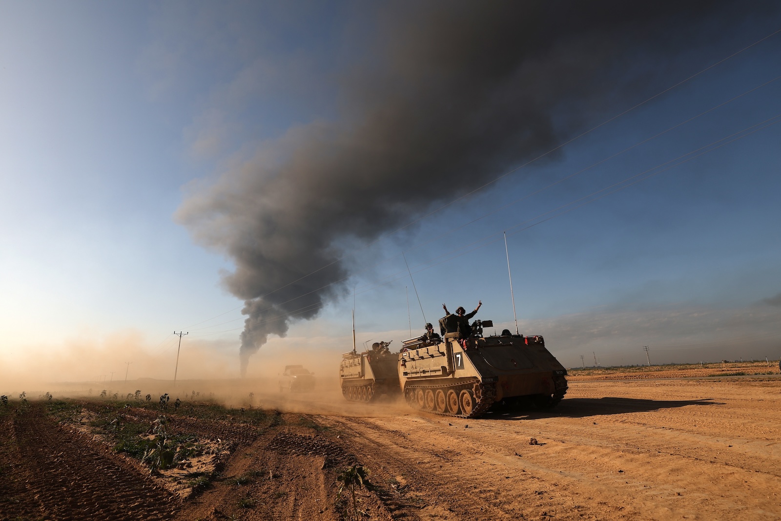 epa11094194 Israeli APCs patrolling along the southern part of the border with the Gaza Strip, as smoke billows from the area near Khan Yunis in the background, 21 January 2024. More than 25,000 Palestinians and at least 1,300 Israelis have been killed, according to the Palestinian Health Ministry and the Israel Defense Forces (IDF), since Hamas militants launched an attack against Israel from the Gaza Strip on 07 October, and the Israeli operations in Gaza and the West Bank which followed it.  EPA/ATEF SAFADI
