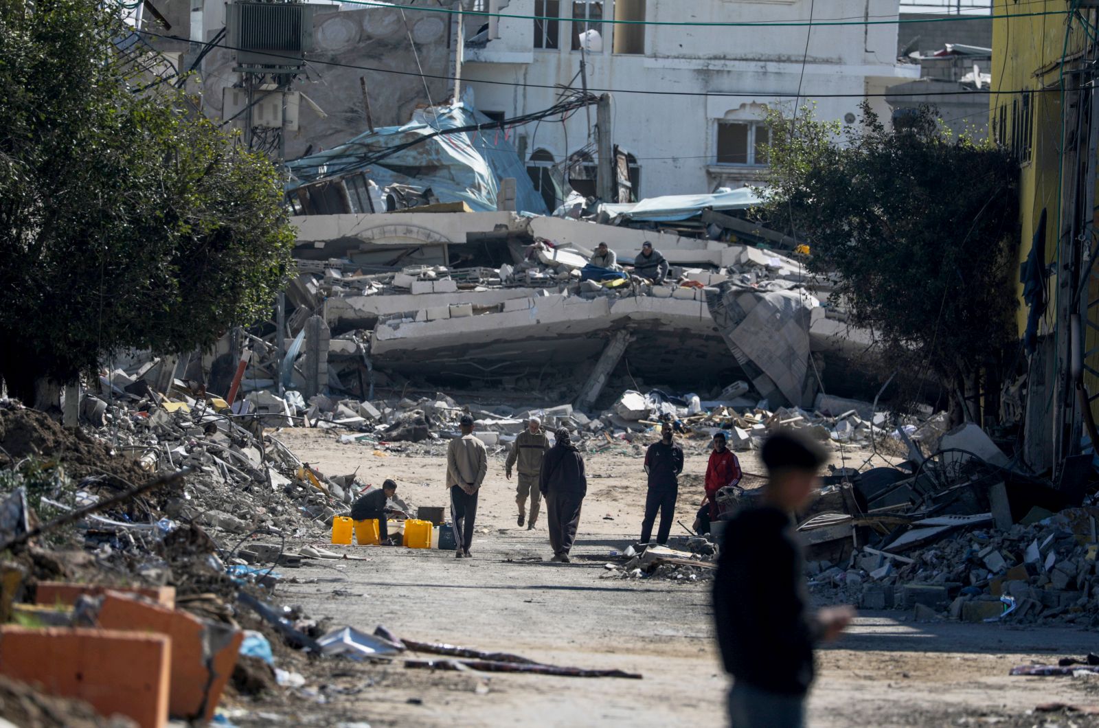 epa11161723 Palestinians walk next to destroyed houses following Israeli military operation in Al Maghazi refugee camp, southern Gaza Strip, 17 February 2024. More than 28,800 Palestinians and over 1,300 Israelis have been killed, according to the Palestinian Health Ministry and the Israel Defense Forces (IDF), since Hamas militants launched an attack against Israel from the Gaza Strip on 07 October 2023, and the Israeli operations in Gaza and the West Bank which followed it.  EPA/MOHAMMED SABER