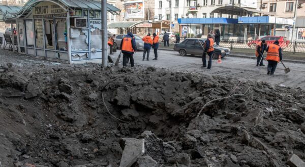 epa11168095 Municipal workers clean a street next to a shelling crater in the aftermath of a shelling in downtown Donetsk, Russian-controlled Ukraine, 20 February 2024. A woman was killed and dozens were injured in the shelling of Kievsky and Voroshilovsky districts of Donetsk, according to city Mayor Alexey Kulemzin.  EPA/VALERY MELNIKOV