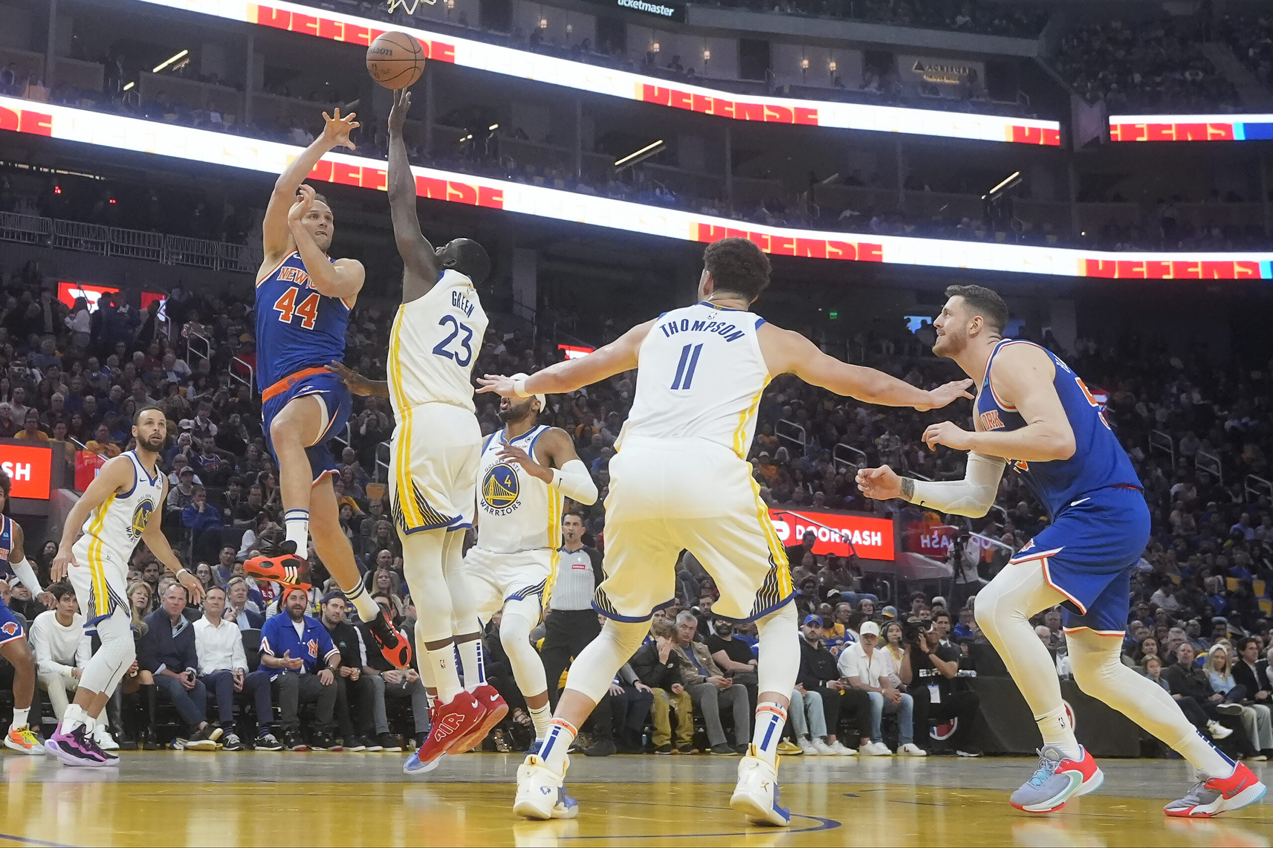 New York Knicks forward Bojan Bogdanovic (44) passes the ball while being defended by Golden State Warriors forward Draymond Green (23) during the first half of an NBA basketball game in San Francisco, Monday, March 18, 2024. (AP Photo/Jeff Chiu)