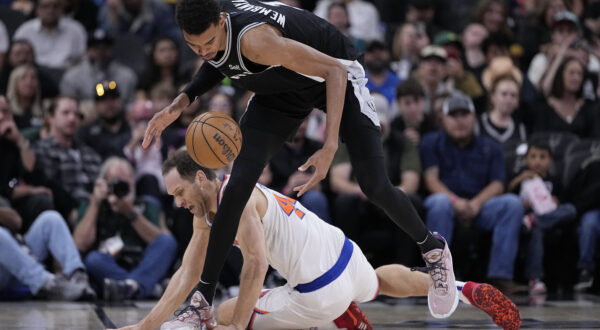 San Antonio Spurs center Victor Wembanyama (1) and New York Knicks forward Bojan Bogdanovic (44) scramble for a loose ball during the first half of an NBA basketball game in San Antonio, Friday, March 29, 2024. (AP Photo/Eric Gay)