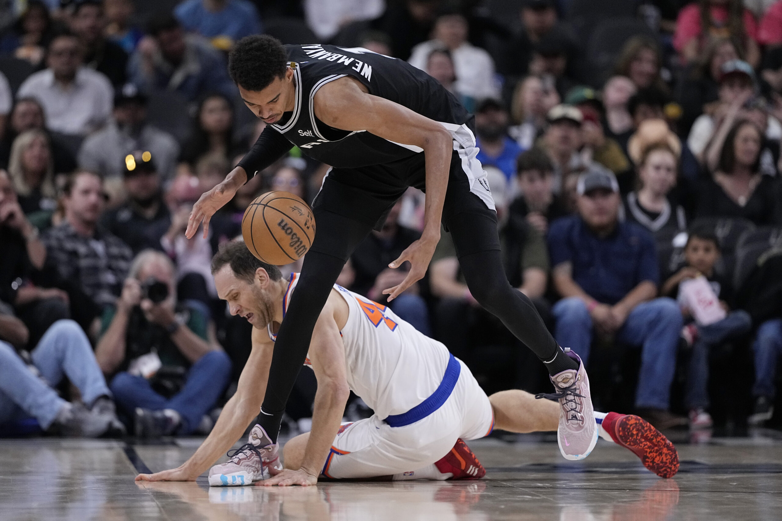 San Antonio Spurs center Victor Wembanyama (1) and New York Knicks forward Bojan Bogdanovic (44) scramble for a loose ball during the first half of an NBA basketball game in San Antonio, Friday, March 29, 2024. (AP Photo/Eric Gay)