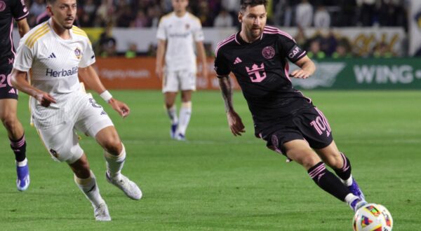 epa11181791 Inter Miami midfielder Lionel Messi (R) kicks the ball as Los Angeles Galaxy midfielder Marco Delgado (L) runs up the field during the first half of the Major League Soccer (MLS) match between LA Galaxy and Inter Miami at Dignity Health Sports Park in Los Angeles, California, USA, 25 February 2024.  EPA/ALLISON DINNER