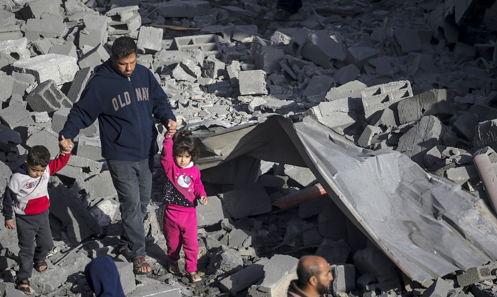 epa11198392 A Palestinian man with two children walks among the rubble of a destroyed house following Israeli air strikes in Al Nusairat refugee camp, Gaza Strip, 04 March 2024. More than 30,500 Palestinians and over 1,300 Israelis have been killed, according to the Palestinian Health Ministry and the Israel Defense Forces (IDF), since Hamas militants launched an attack against Israel from the Gaza Strip on 07 October 2023, and the Israeli operations in Gaza and the West Bank which followed it.  EPA/MOHAMMED SABER