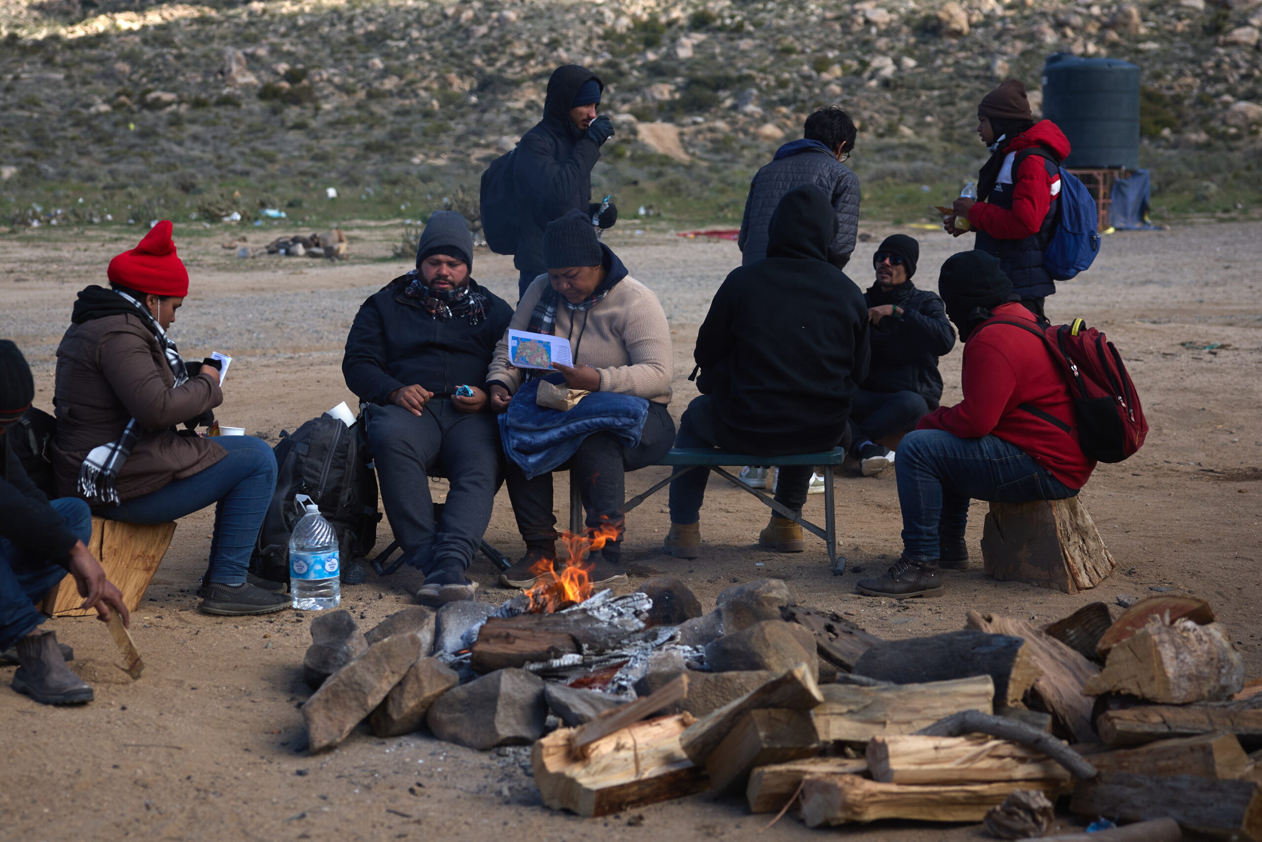 epa11199433 Migrants sit by a fire and wait for US Border Patrol in Jacumba, California, USA, 04 March 2024. According to authorities, the number of people crossing illegally into the United States from Mexico has dropped significantly over the first couple of months of 2024 as US President Biden comes under pressure from both parties over border security. President Biden has been working on a new bipartisan border security bill, but has been unable to get it passed through Congress.  EPA/ALLISON DINNER