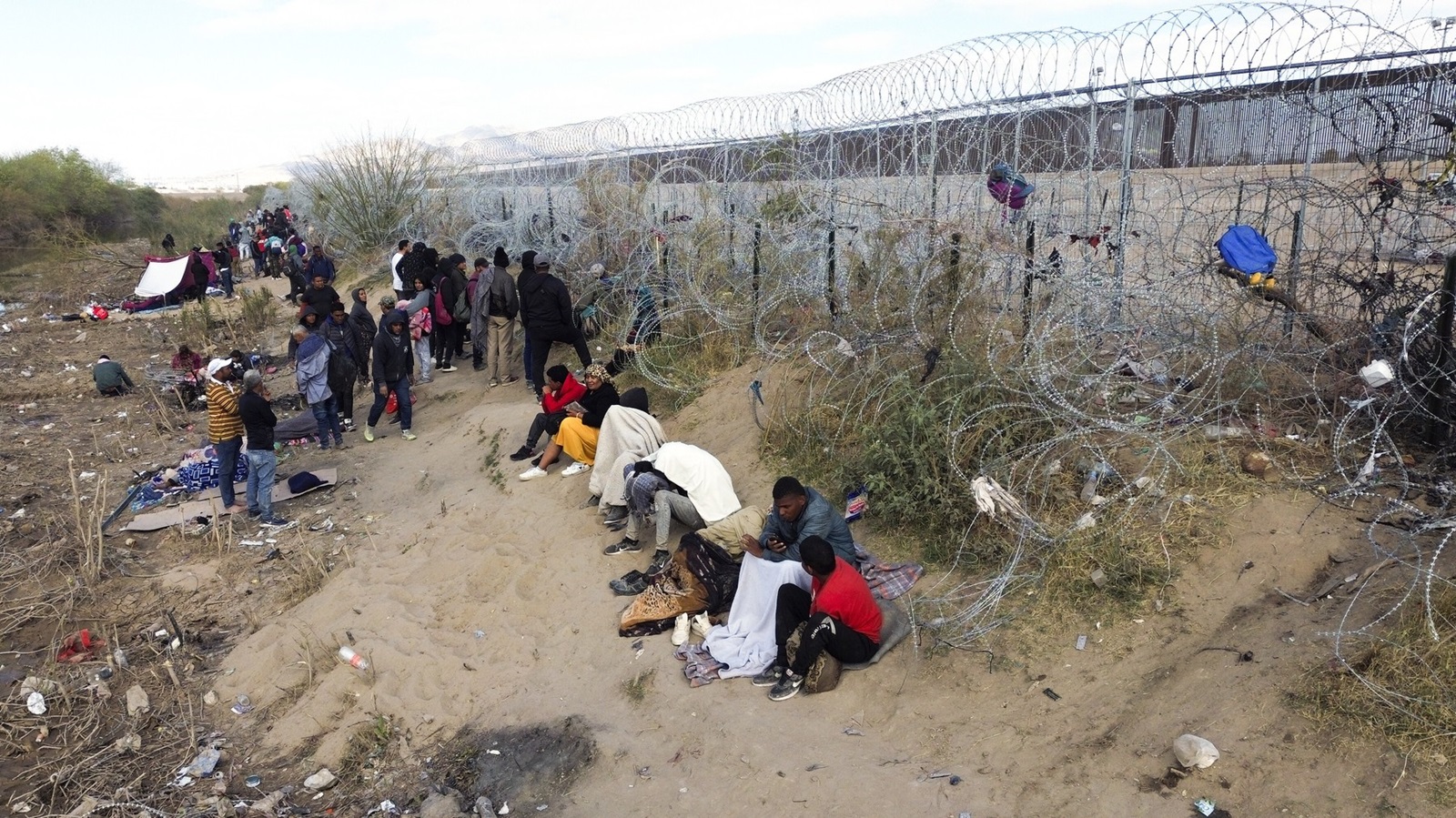 CIUDAD JUAREZ , MEXICO - MARCH 19: Some lying down, others standing, among garbage and wire with razor blades, migrants try to persuade the agents of the Texas National Guard to open the fence, which is guarded, installed days ago with the intention of complicating the crossing of migrants who reach this border in Ciudad Juarez, Mexico on March 19, 2024. The blockade is permanent by the military, so migrants choose to set up a camp on the side of Rio Bravo, a bonfire makes them gather near it, four blankets serve as shelter against the few rays of the sun on the cloudy morning of Tuesday to a family. Christian Torres / Anadolu,Image: 858095375, License: Rights-managed, Restrictions: , Model Release: no, Credit line: AA/ABACA / Abaca Press / Profimedia