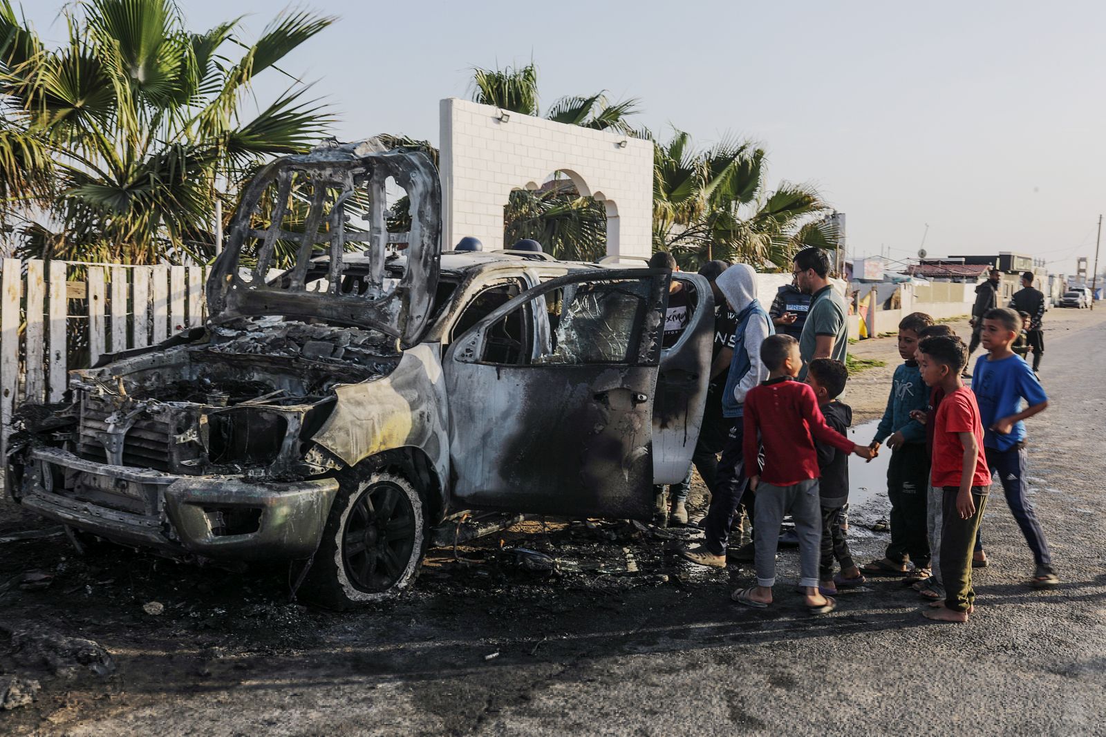 epa11255094 People stand near a destroyed car of the NGO World Central Kitchen (WCK) along Al Rashid road, between Deir Al Balah and Khan Younis in the southern Gaza Strip, 02 April 2024. According to the Palestinian Red Crescent, at least four people from the NGO World Central Kitchen (WCK) were killed when a missile hit their convoy in Deir al Balah while they were on their way from Rafah to Gaza City to receive fresh aid delivered by the Open Arms vessel. The victims were confirmed to be a British, a Polish and an Australian citizen, while the nationality of the fourth victim was still unknown.  EPA/MOHAMMED SABER  EPA-EFE/MOHAMMED SABER