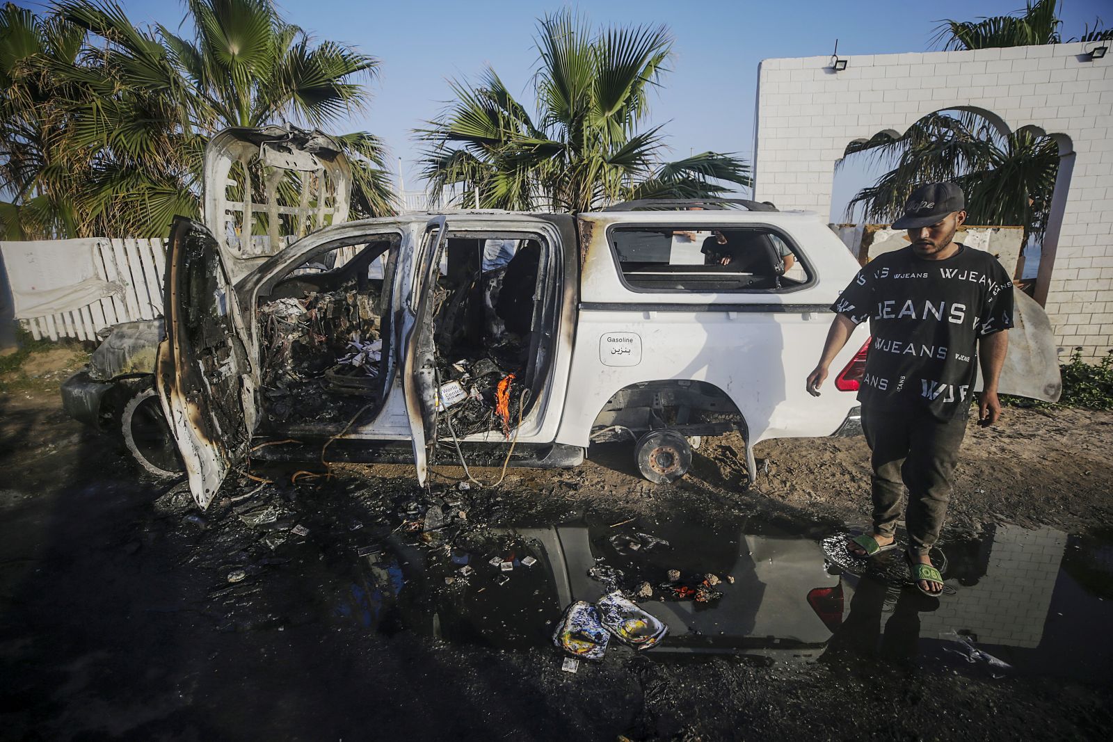 epa11255137 A man stands near a destroyed car of the NGO World Central Kitchen (WCK) along Al Rashid road, between Deir Al Balah and Khan Younis in the southern Gaza Strip, 02 April 2024. According to the Palestinian Red Crescent, at least four people from the NGO World Central Kitchen (WCK) were killed when a missile hit their convoy in Deir al Balah while they were on their way from Rafah to Gaza City to receive fresh aid delivered by the Open Arms vessel. The victims were confirmed to be a British, a Polish and an Australian citizen, while the nationality of the fourth victim was still unknown.  EPA/MOHAMMED SABER