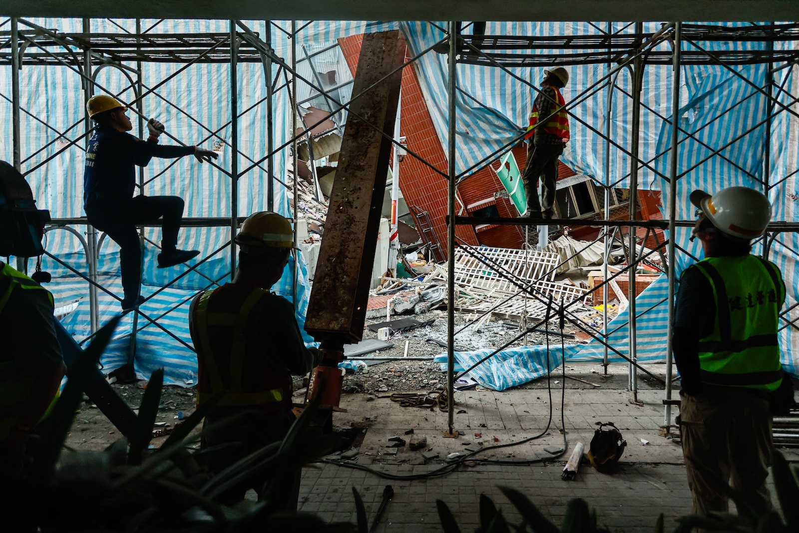 epa11261851 Workers climb up the scaffolding as they demolish the partially collapsed residential building Uranus, following the 03 April earthquake in Hualien, Taiwan, 06 April 2024. Although the government has been working to restore the city after the strongest earthquake in 25 years, the business and tourist sectors in Hualien have been affected, resulting in significant economic losses.  EPA/DANIEL CENG