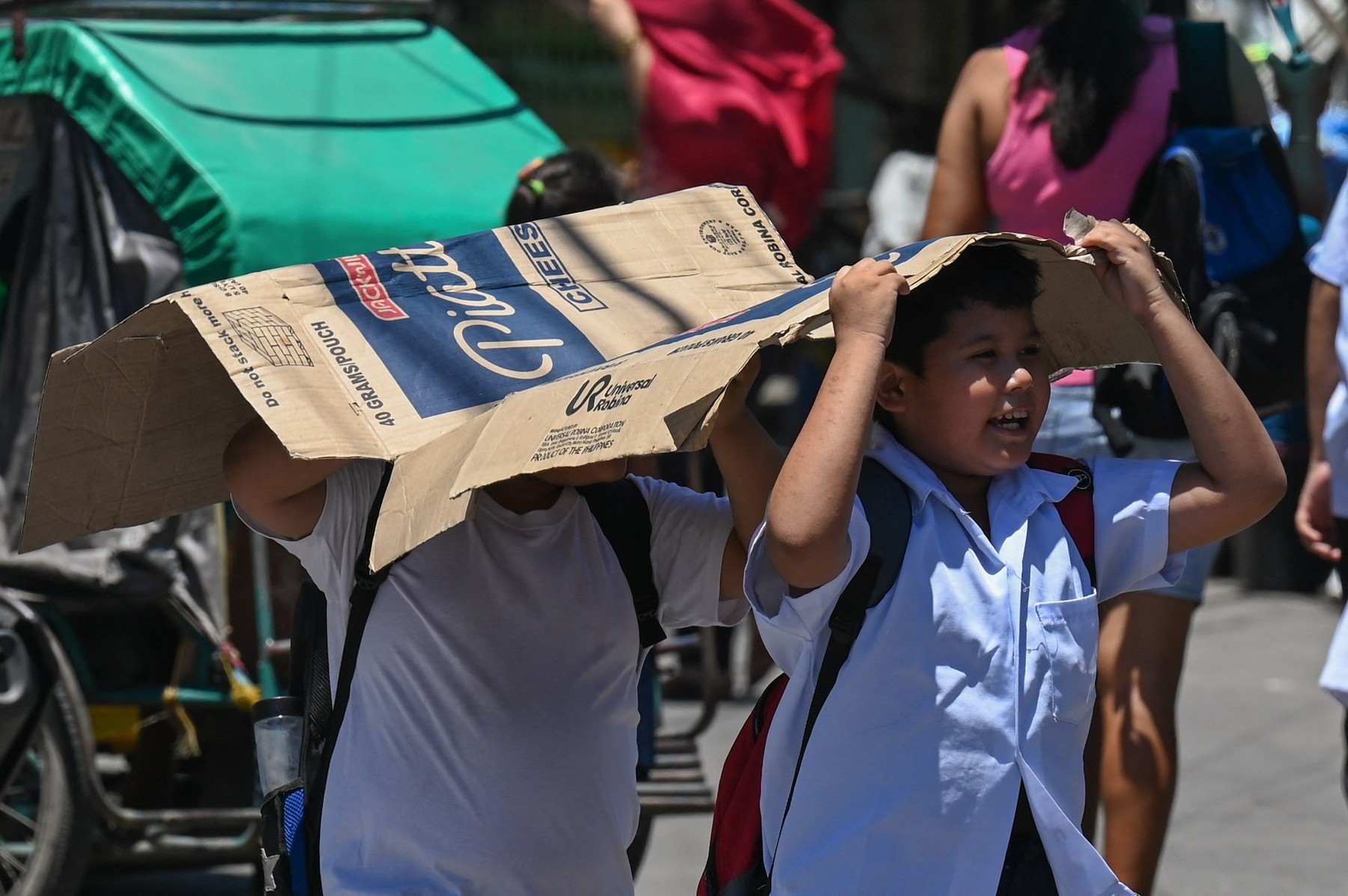 Students use a cardboard to protect themselves from the sun during a hot day in Manila on April 2, 2024.  More than a hundred schools in the Philippine capital shut their classrooms on April 2, as the tropical heat hit "danger" levels, education officials said.,Image: 861698799, License: Rights-managed, Restrictions: , Model Release: no, Credit line: JAM STA ROSA / AFP / Profimedia