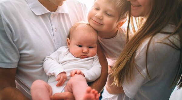Mother and father are holding a baby in their arms. Big brother hugs his sister. Care and health. Happy young family.,Image: 516296696, License: Royalty-free, Restrictions: , Model Release: yes, Credit line: Vlad Dmytrenko / Alamy / Alamy / Profimedia
