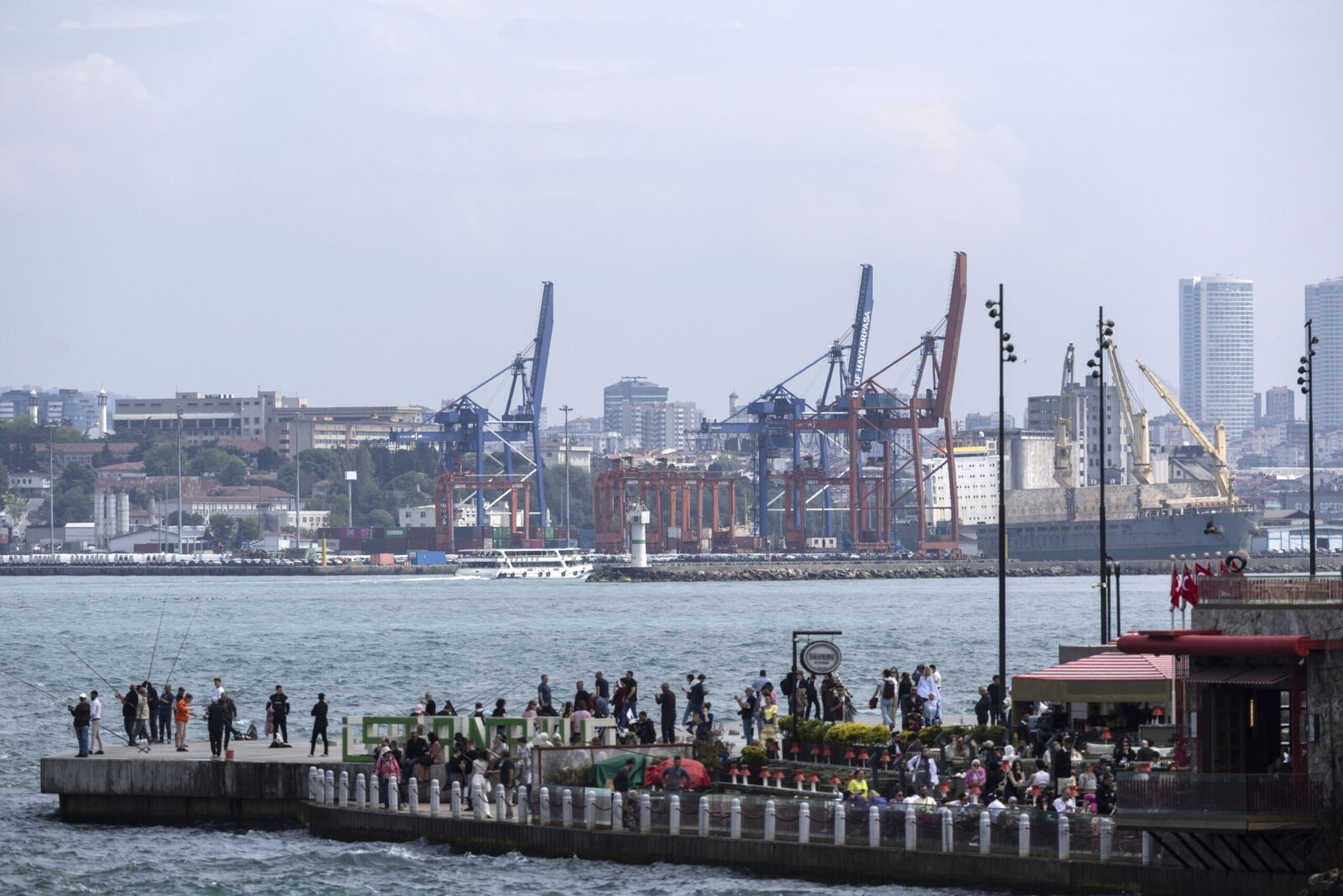 epa11316115 People stand on a pier in the Bosphorus Strait before the Haydarpasa port (back) in Istanbul, Turkey 03 May 2024. The Turkish trade ministry announced that Turkey has halted all trade with Israel citing a 'worsening humanitarian tragedy' in the Gaza Strip. The ministry said that all export and import deals pertaining to Israel had been suspended and would not be resumed until Israel allows for 'an uninterrupted and sufficient flow of humanitarian aid to Gaza.'  EPA/TOLGA BOZOGLU