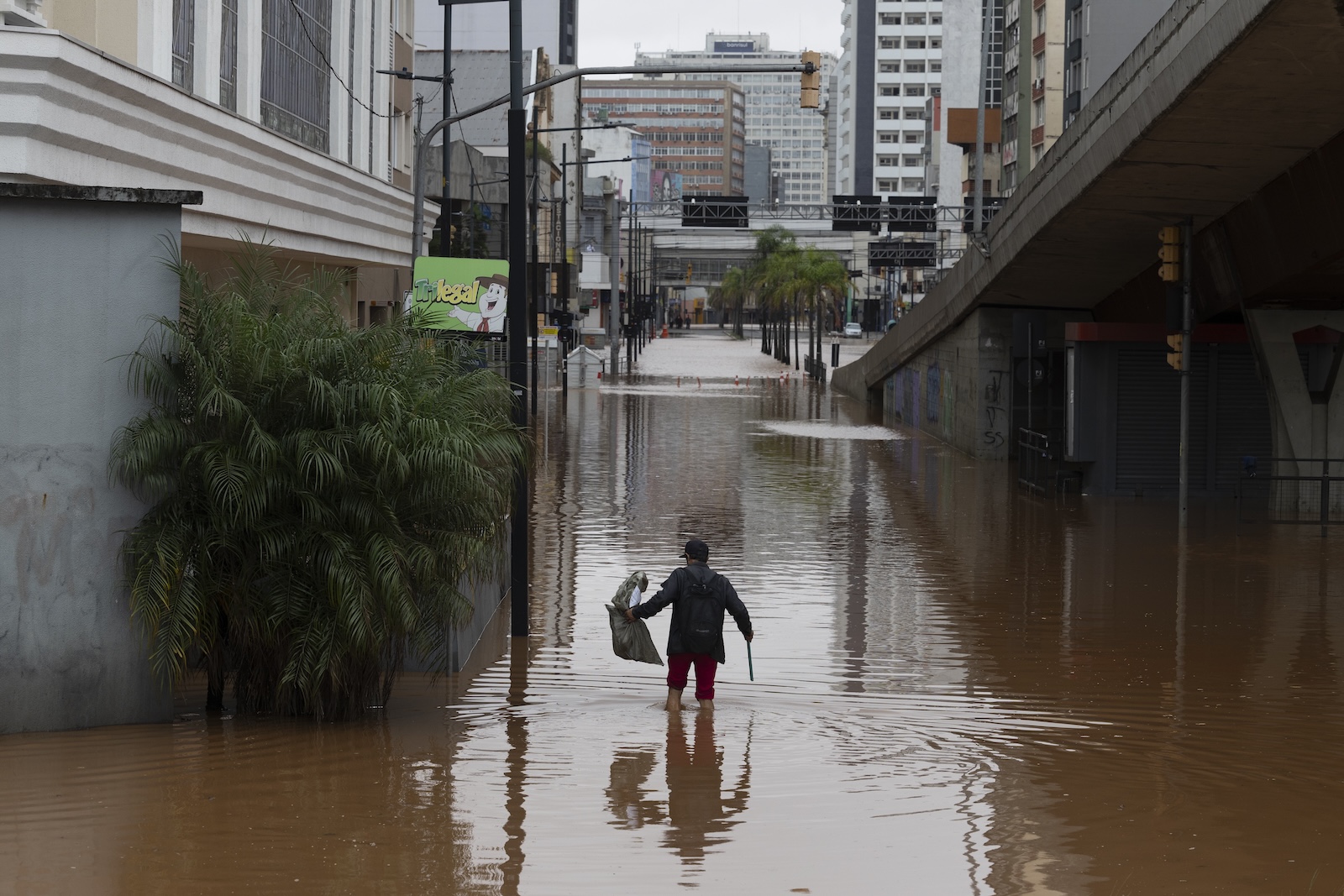 epa11316996 A man wades in a flooded street in the center of Porto Alegre, Brazil, 03 May 2024. Regional authorities reported that at least 37 people died and 60 are missing as a result of heavy rains that have affected the Brazilian state of Rio Grande do Sul in recent days. Due to the magnitude of the tragedy, the governor of the state, Eduardo Leite, decreed a state of public calamity for a period of 180 days throughout Rio Grande do Sul.  EPA/ISAAC FONTANA
