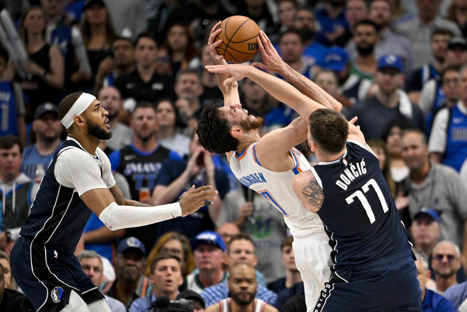May 13, 2024; Dallas, Texas, USA; Dallas Mavericks guard Luka Doncic (77) fouls Oklahoma City Thunder forward Chet Holmgren (7) as center Daniel Gafford (21) looks on during the second half in game four of the second round for the 2024 NBA playoffs at American Airlines Center. Mandatory Credit: Jerome Miron-USA TODAY Sports Photo: Jerome Miron/REUTERS