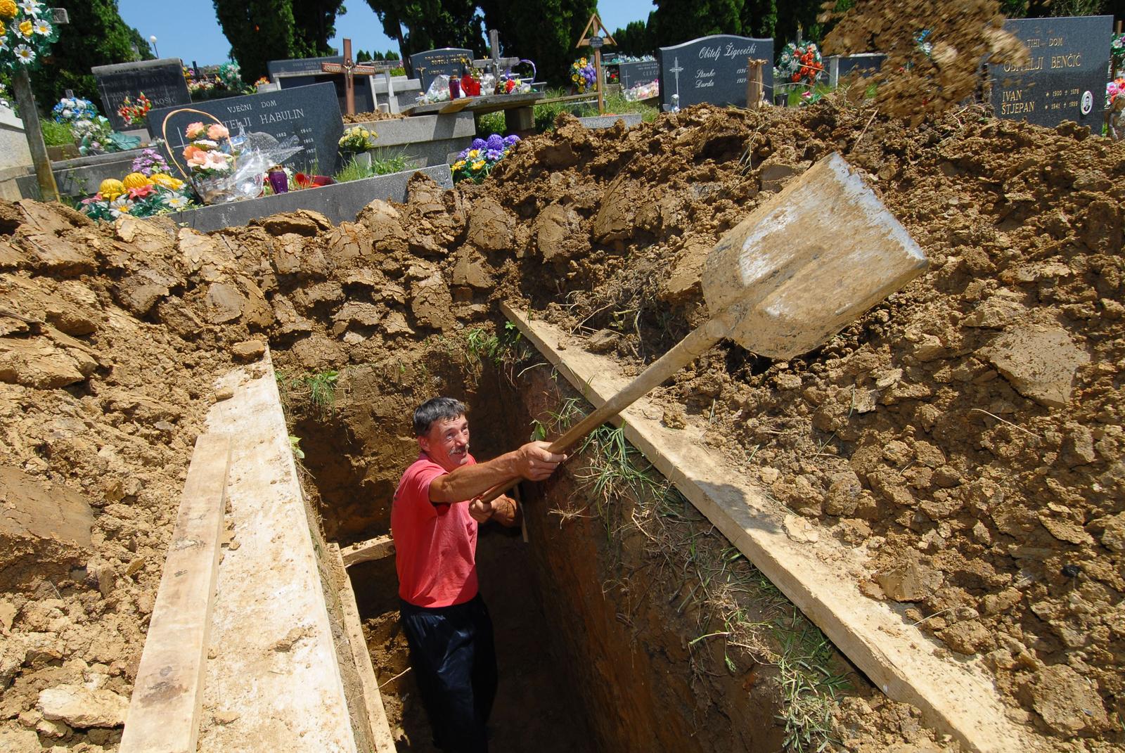 17.07.2009., Mace, Hrvatska - Prije nego sto su se poceli baviti tim poslom, grobari su bili stolari, gradevinarci, radili utvornicama i sl. Posao grobara prihvatili su zbog stalnog zaposlenja i pristojne place. Darko Pavor koji je i komunalni radnik u Macu kopa raku za sprovod.rPhoto: Zeljko Pusec/Vecernji list
