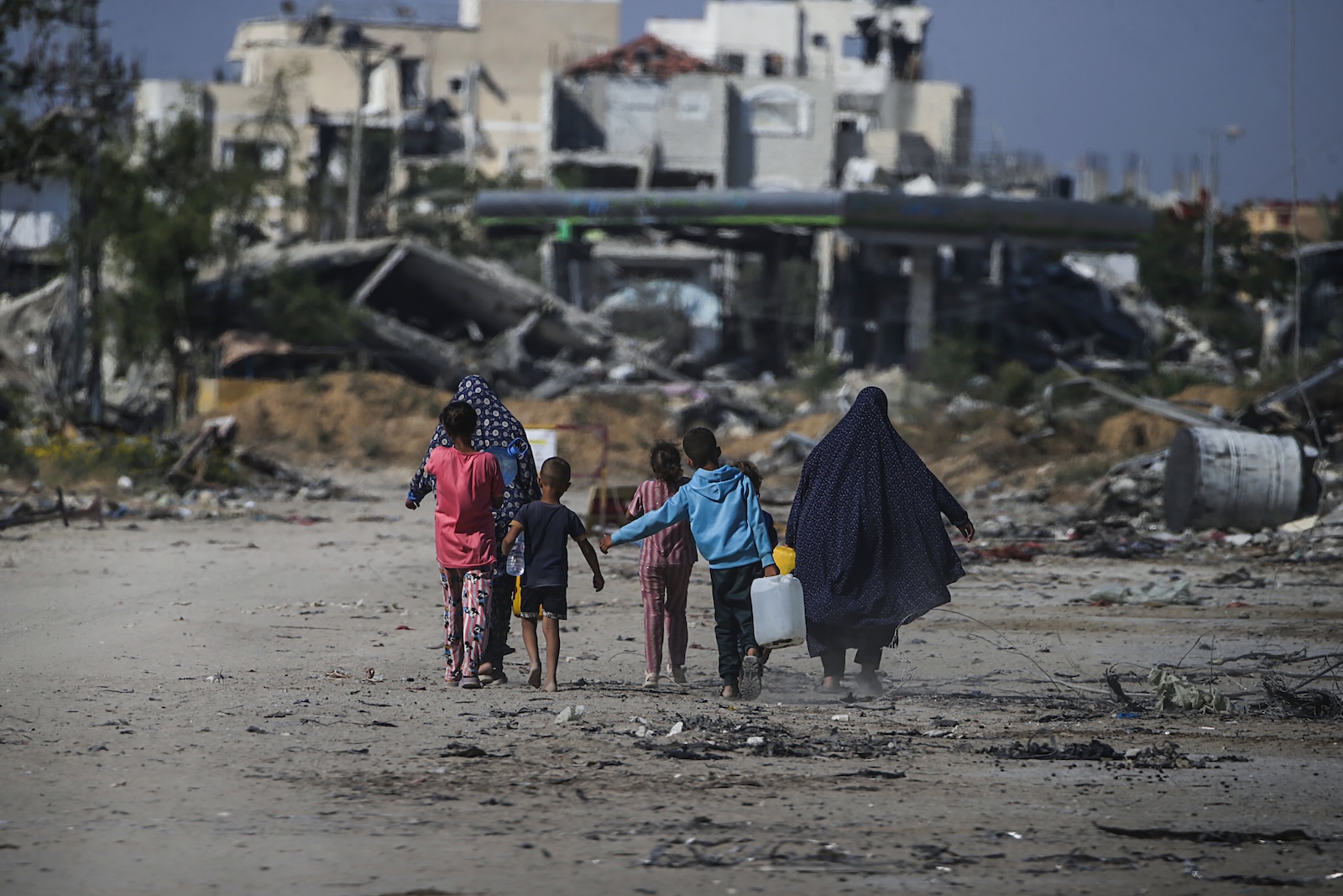 epaselect epa11392513 Internally displaced Palestinians walk next to destroyed buildings in Khan Younis, southern Gaza Strip, 05 June 2024. More than 36,000 Palestinians and over 1,400 Israelis have been killed, according to the Palestinian Health Ministry and the Israel Defense Forces (IDF), since Hamas militants launched an attack against Israel from the Gaza Strip on 07 October 2023, and the Israeli operations in Gaza and the West Bank which followed it.  EPA/MOHAMMED SABER