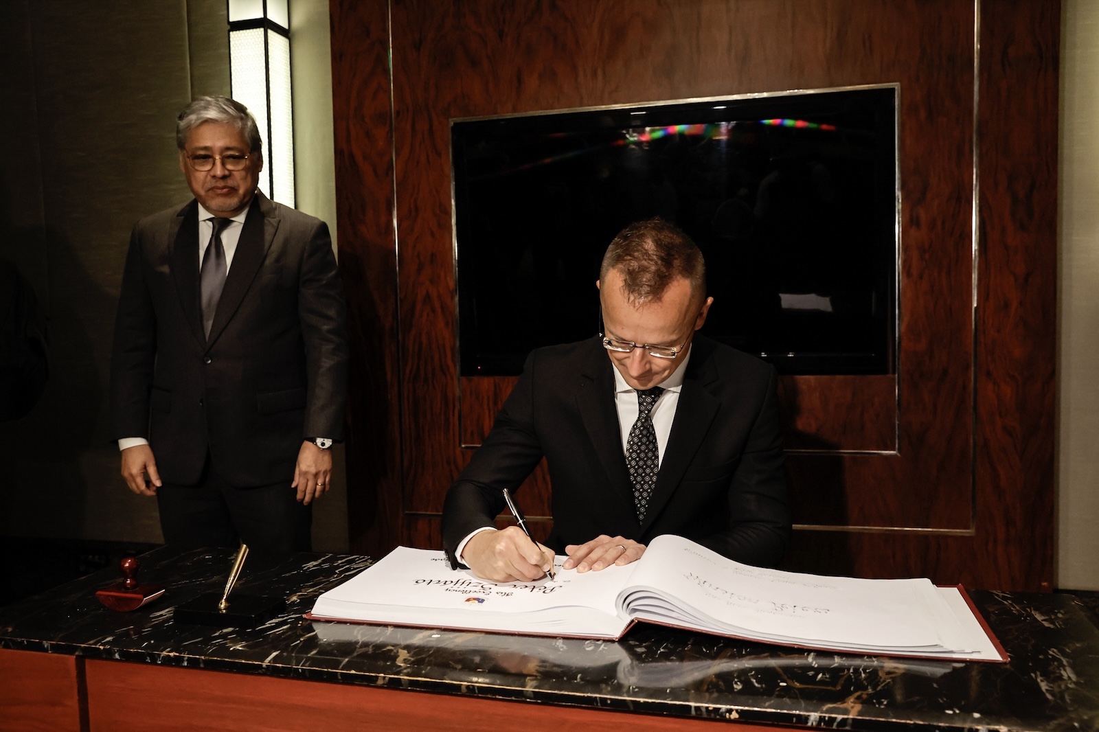 epa11407170 Philippine Secretary of Foreign Affairs Enrique Manalo (L) looks on as Hungarian Minister of Foreign Affairs and Trade Peter Szijjarto (R) signs a guest book inside a receiving room of a conference hall in Makati City, Metro Manila, Philippines, 13 June 2024. The two officials and their respective delegations will hold bilateral talks to boost cooperation in various sectors of both nations.  EPA/ROLEX DELA PENA