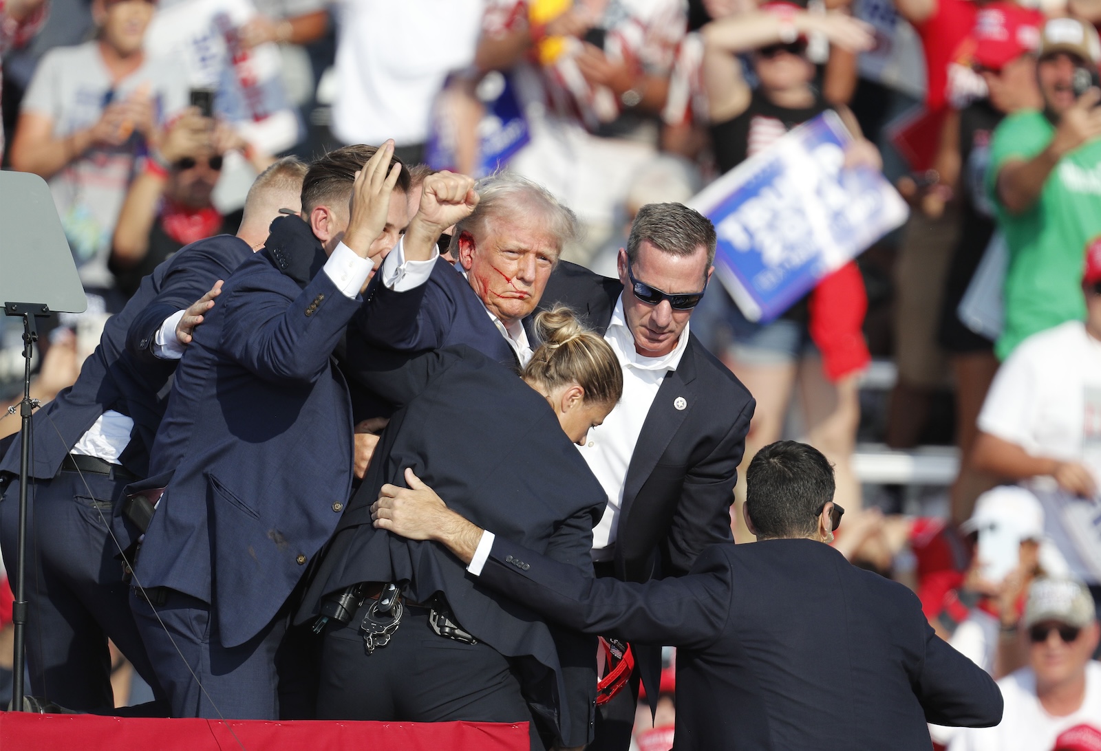 epa11476785 Former US President Donald Trump pumps his fist as he is rushed from stage by secret service after an incident during a campaign rally at the Butler Farm Show Inc. in Butler, Pennsylvania, USA, 13 July 2024. Trump was rushed off stage by secret service after an incident during a campaign rally in Pennsylvania. According to the Butler County district attorney a suspected gunman was dead and at least one rally attendee was killed. According to a statement by a secret service spokesperson, the former President is safe and further information on the incident will be released when available.  EPA/DAVID MAXWELL