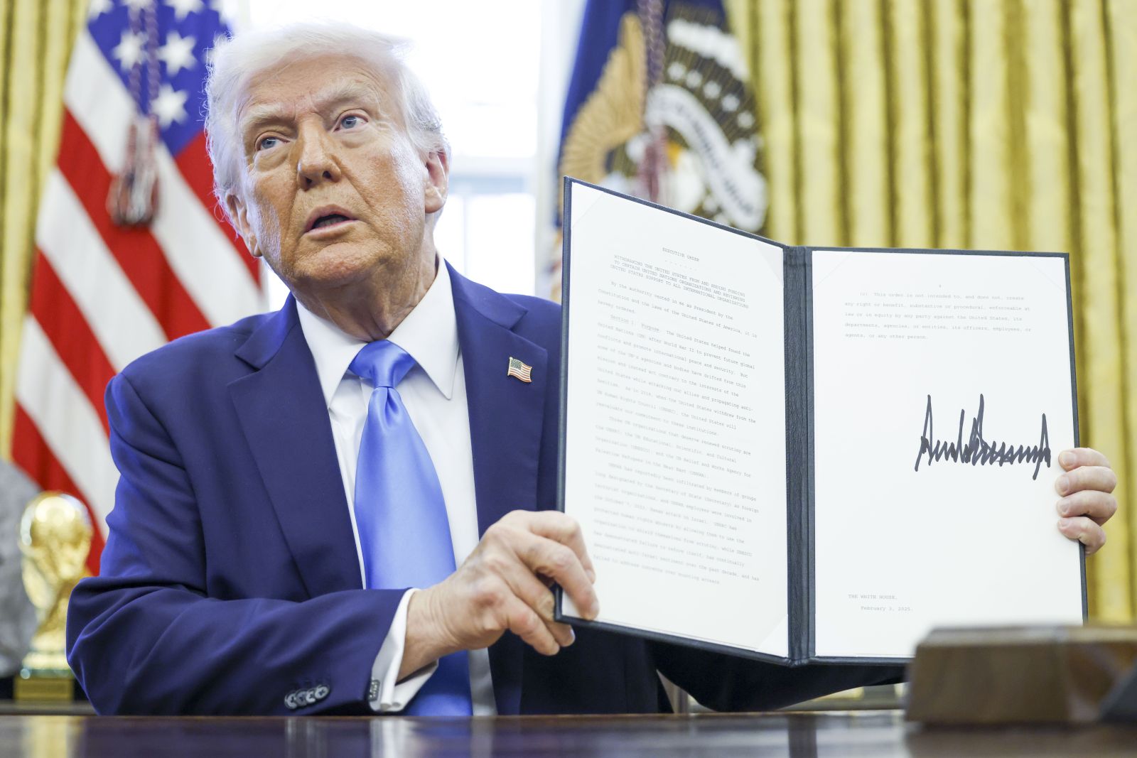 epa11875453 US President Donald Trump holds up a newly signed executive order withdrawing the United States from the United Nations Human Rights Council in the Oval Office of the White House in Washington, DC, USA, 04 February 2025.  EPA/SHAWN THEW / POOL