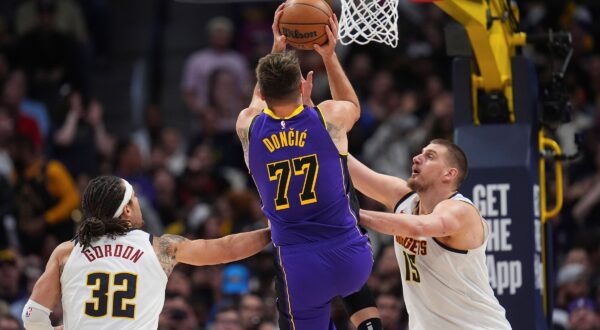 Los Angeles Lakers guard Luka Doncic (77) drives to the basket between Denver Nuggets forward Aaron Gordon (32) and center Nikola Jokic (15) in the second half of an NBA basketball game Saturday, Feb. 22, 2025, in Denver. (AP Photo/David Zalubowski) Lakers Nuggets Basketball