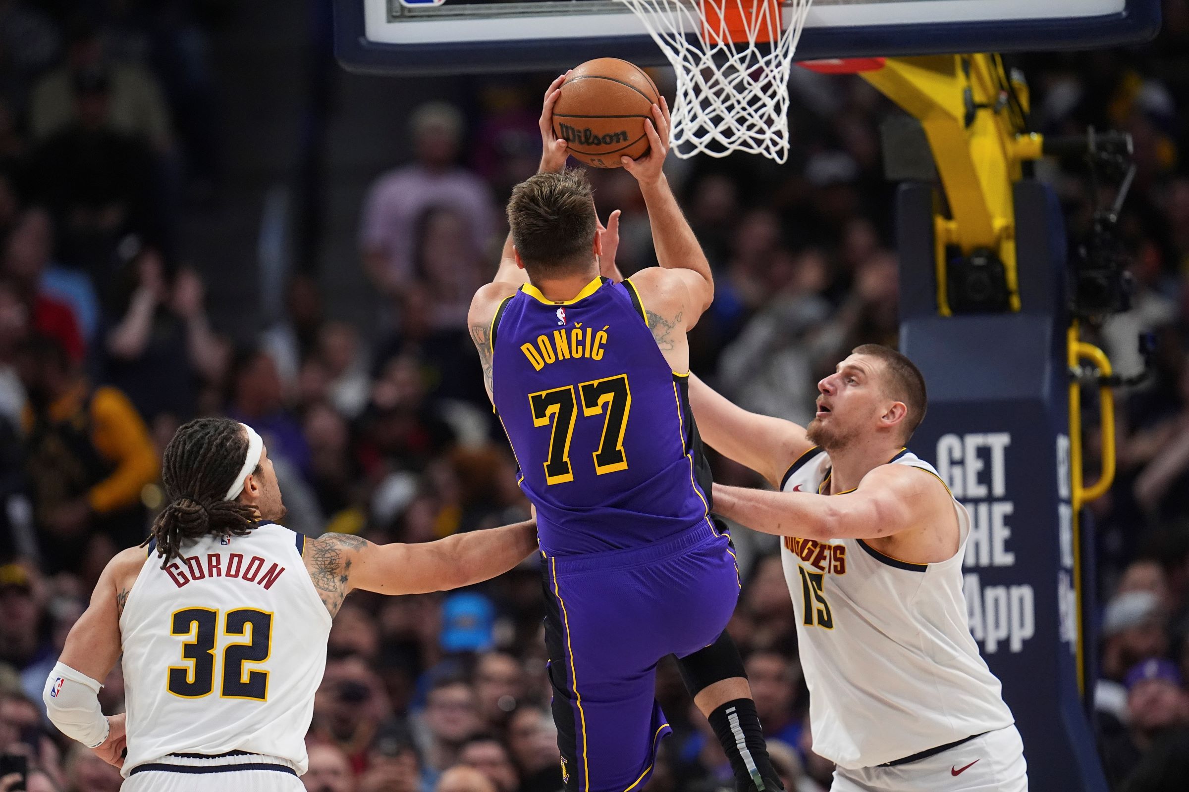 Los Angeles Lakers guard Luka Doncic (77) drives to the basket between Denver Nuggets forward Aaron Gordon (32) and center Nikola Jokic (15) in the second half of an NBA basketball game Saturday, Feb. 22, 2025, in Denver. (AP Photo/David Zalubowski) Lakers Nuggets Basketball