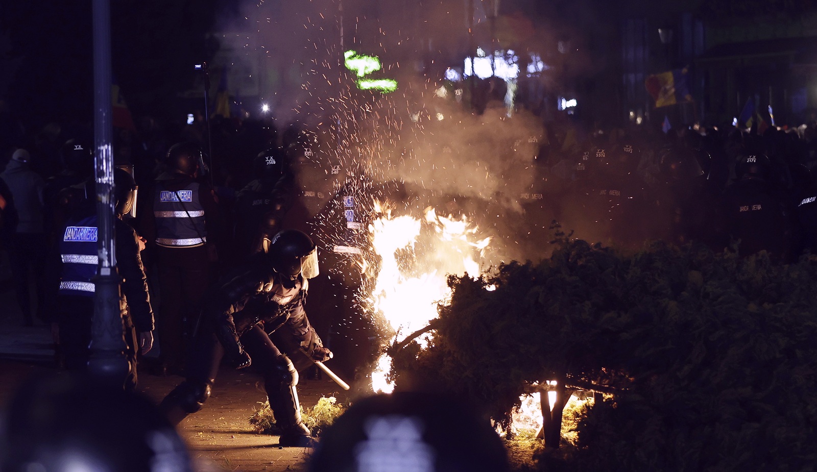 epa11952860 A riot-policeman tries to extinguish a street decoration set on fire by protesters while his colleagues scuffle with Calin Georgescu's supporters during a protest that turned violent in front of Central Elections Bureau (BEC) after Georgescu's candidacy was invalidated, in Bucharest, Romania, late 09 March 2025. Calin Georgescu, the independent candidate who won the first round of Romania's annulled presidential elections, registered his candidacy at Central Elections Bureau on Friday 07 March 2025. Former independent presidential candidate Calin Georgescu was questioned by prosecutors on 26 February 2025 as part of an investigation into election campaign fraud, including actions against the constitutional order and false statements about campaign financing. A judge from the Prosecutor General's Office imposed a judicial control measure, which Georgescu appealed. Romanians will vote in the first round of the presidential elections on 4 May 2025.  EPA/ROBERT GHEMENT