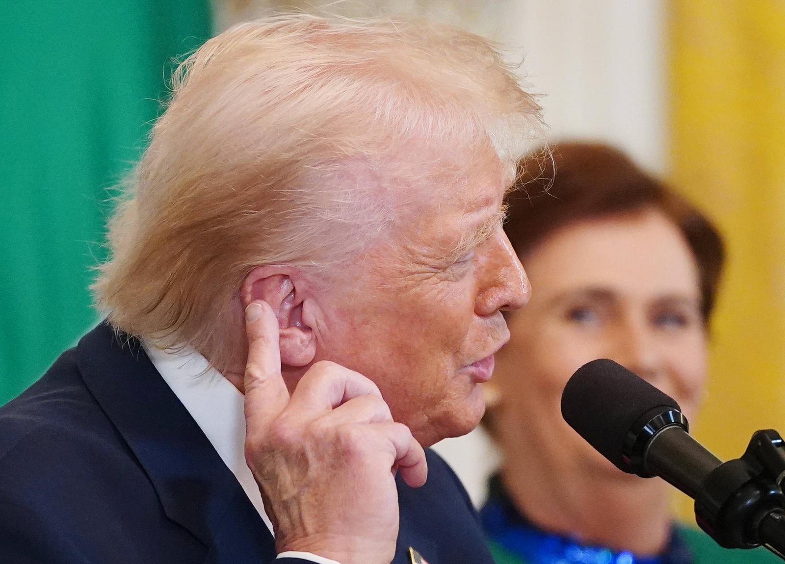 United States President Donald Trump points to his ear where he was shot during an assassination attempt on July 13, 2024, as he speaks during a St Patricks Day reception with the Taoiseach Prime Minister Michael Martin of Ireland in the East Room of the White House in Washington, DC on Wednesday, March 12, 2025. Copyright: xBonniexCashx/xPoolxviaxCNPx/MediaPunchx Photo: IMAGO/Bonnie Cash / Pool via CNP /MediaPunch/IMAGOSTOCK&PEOPLE