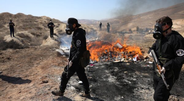 epa11923609 Syrian police officers secure the area as they burn drugs in Damascus, Syria, 25 February 2025. Syria’s new authorities burned hundreds of tons of narcotic pill Captagon as well as bags of hashish, at the headquarters of the fourth division in Damascus.  EPA/MOHAMMED AL RIFAI