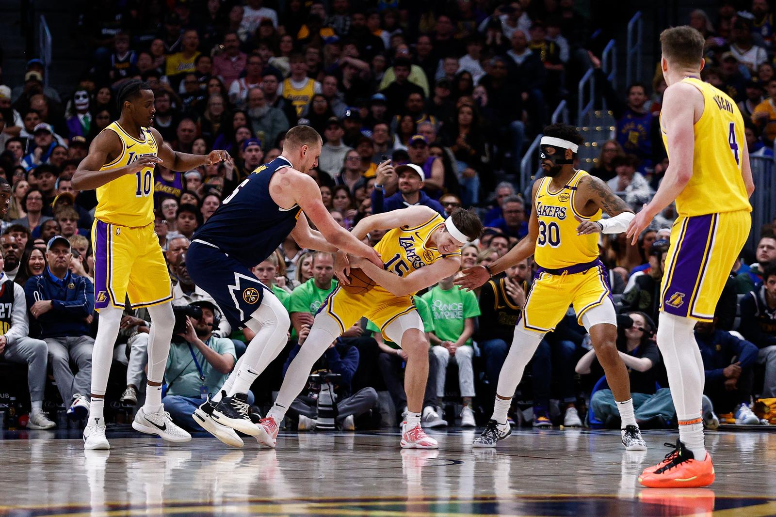 Mar 14, 2025; Denver, Colorado, USA; Los Angeles Lakers guard Austin Reaves (15) steals the ball away from Denver Nuggets center Nikola Jokic (15) as center Christian Koloko (10) and guard Jordan Goodwin (30) defend in the fourth quarter at Ball Arena. Mandatory Credit: Isaiah J. Downing-Imagn Images Photo: Isaiah J. Downing/REUTERS