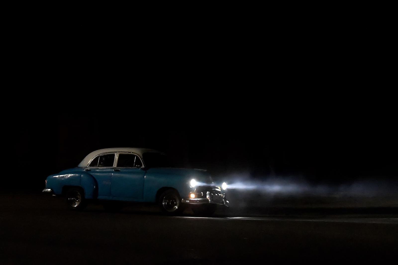 (250217) -- HAVANA, Feb. 17, 2025 (Xinhua) -- A vintage car drives along a dark avenue after a power outage in Havana, Cuba, on Feb. 15, 2025.   Cuba's Ministry of Labor and Social Security announced on Feb. 13 that given the current power situation, all non-essential educational and work activities were suspended on Feb. 14 and 15.   Due to U.S. sanctions, the country has long struggled to import fuel and repair its severely aging power generation equipment, leading to a tight nationwide electricity supply. (Photo by Joaquin Hernandez/Xinhua) Photo: JOAQUIN HERNANDEZ/XINHUA