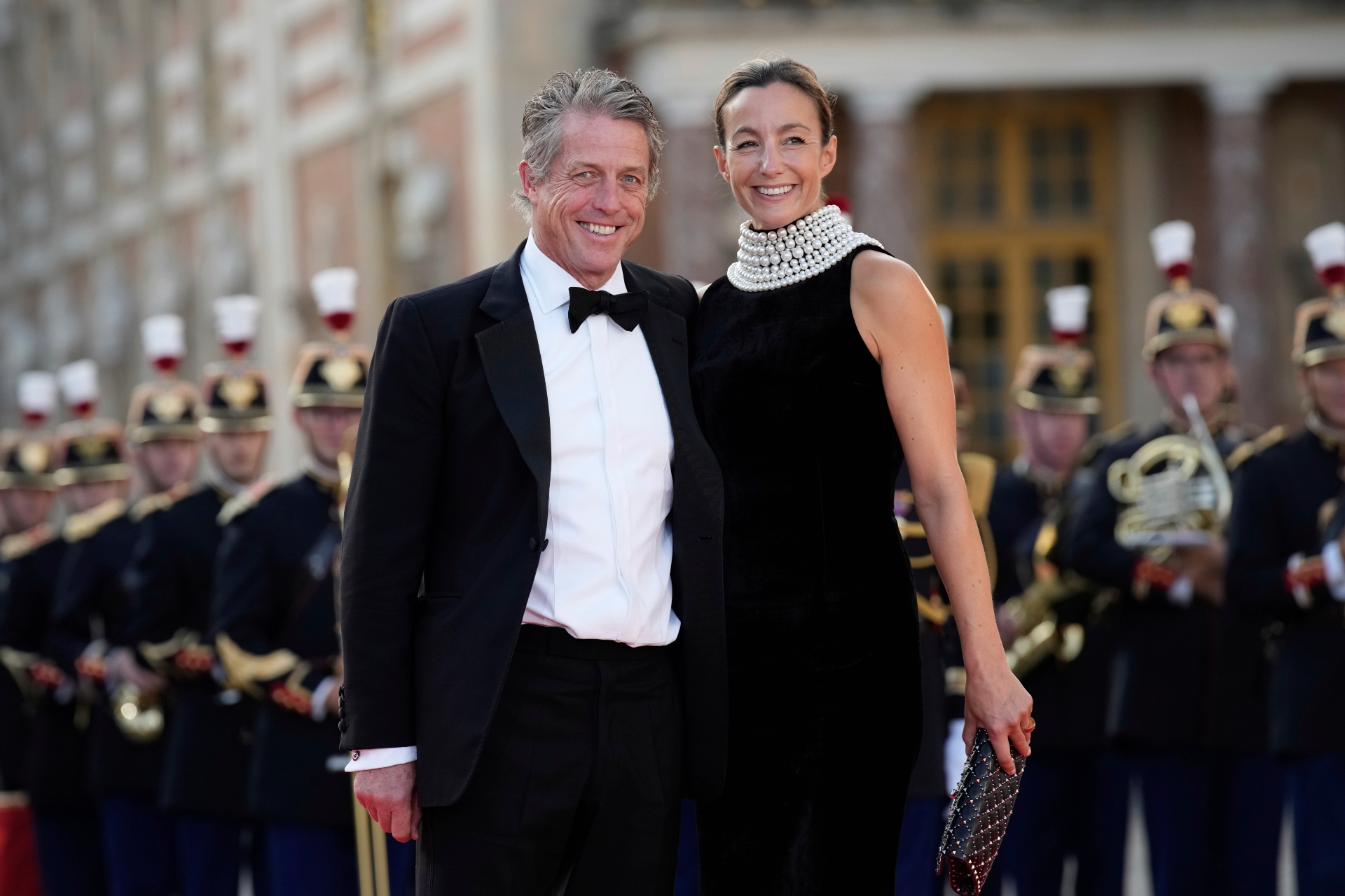 Hugh Grant, left, and Anna Elisabet Eberstein arrive for a state dinner held in honor of King Charles III and Queen Camilla, at the Chateau de Versailles, west of Paris, Wednesday, Sept. 20, 2023. King Charles III of the United Kingdom starts a three-day state visit to France on Wednesday meant to highlight the friendship between the two nations with great pomp, after the trip was postponed in March amid widespread demonstrations against President Emmanuel Macron's pension changes. (AP Photo/Christophe Ena)