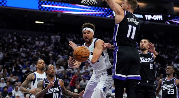 Dallas Mavericks guard Klay Thompson, center, passes the ball while defended by Sacramento Kings center Domantas Sabonis (11) during the first half of an NBA play-in tournament basketball game Wednesday, April 16, 2025, in Sacramento, Calif. (AP Photo/Godofredo A. Vásquez) Mavericks Kings Basketball