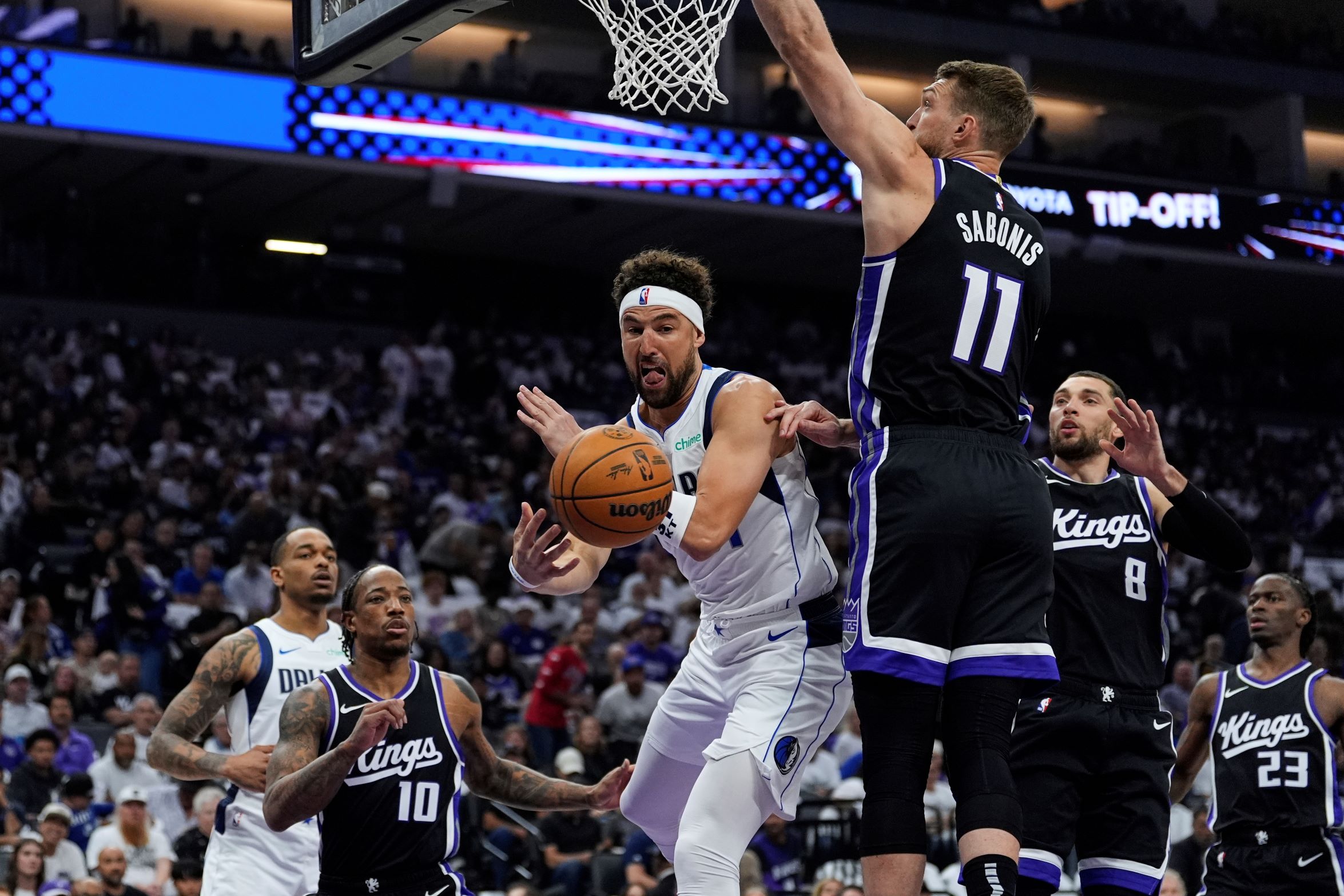 Dallas Mavericks guard Klay Thompson, center, passes the ball while defended by Sacramento Kings center Domantas Sabonis (11) during the first half of an NBA play-in tournament basketball game Wednesday, April 16, 2025, in Sacramento, Calif. (AP Photo/Godofredo A. Vásquez) Mavericks Kings Basketball