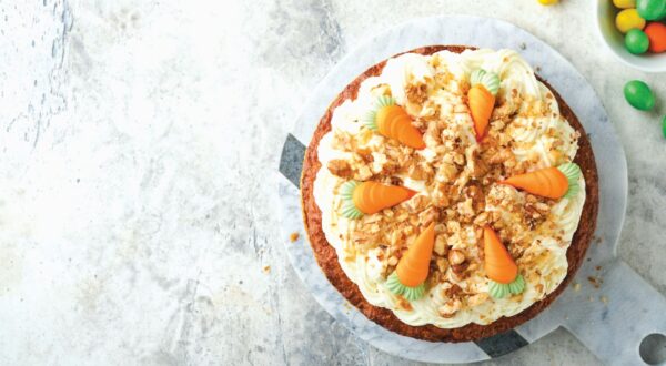 Easter Carrot cake with cream cheese frosting. Delicious carrot cake with walnut and cream cheese frosting on gray concrete background table for festive dinner. Traditional carrot cake. Easter food.
