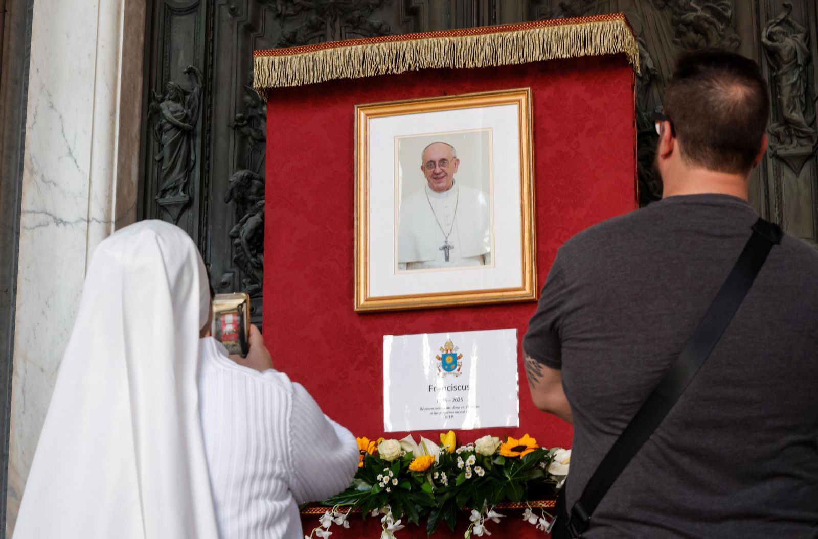 epa12044842 People stand near an image of late Pope Francis at the Basilica of Santa Maria Maggiore in Rome, Italy, 21 April 2025. Pope Francis died on 21 April 2025 at the age of 88, according to the Holy See. Born Jorge Mario Bergoglio in Buenos Aires, Argentina, on 17 December 1936, he was appointed leader of the Catholic Church on 13 March 2013, succeeding Pontiff Emeritus Benedict XVI.  EPA/GIUSEPPE LAMI