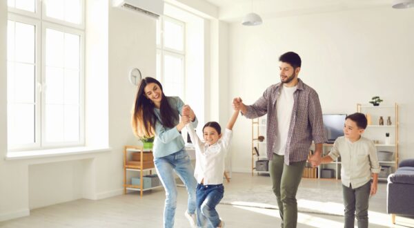 Smiling young parents and cheerful kids daughter and son having fun together at home on weekend with light spacious room interior at backgroundFamily spending happy time at home with children concept